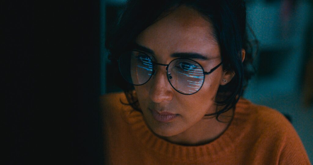 Closeup of Female computer programmer works on complex software development tasks at her home office late into the night. Software developer, artificial intelligence and programming.